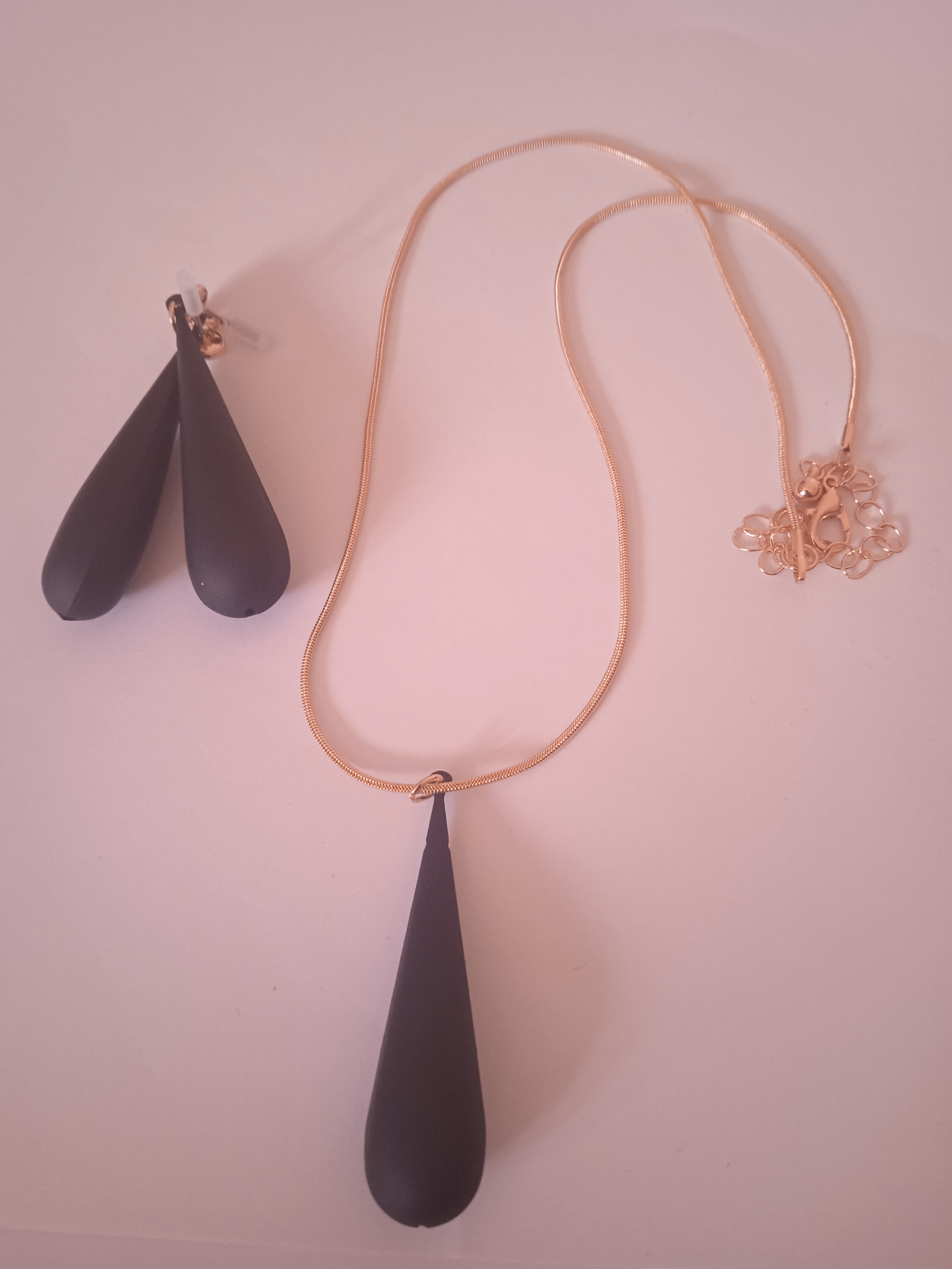 l'ensemble collier pendentif noir allongée femme noir accompagner de son boucle d'oreille noir et doré allongée